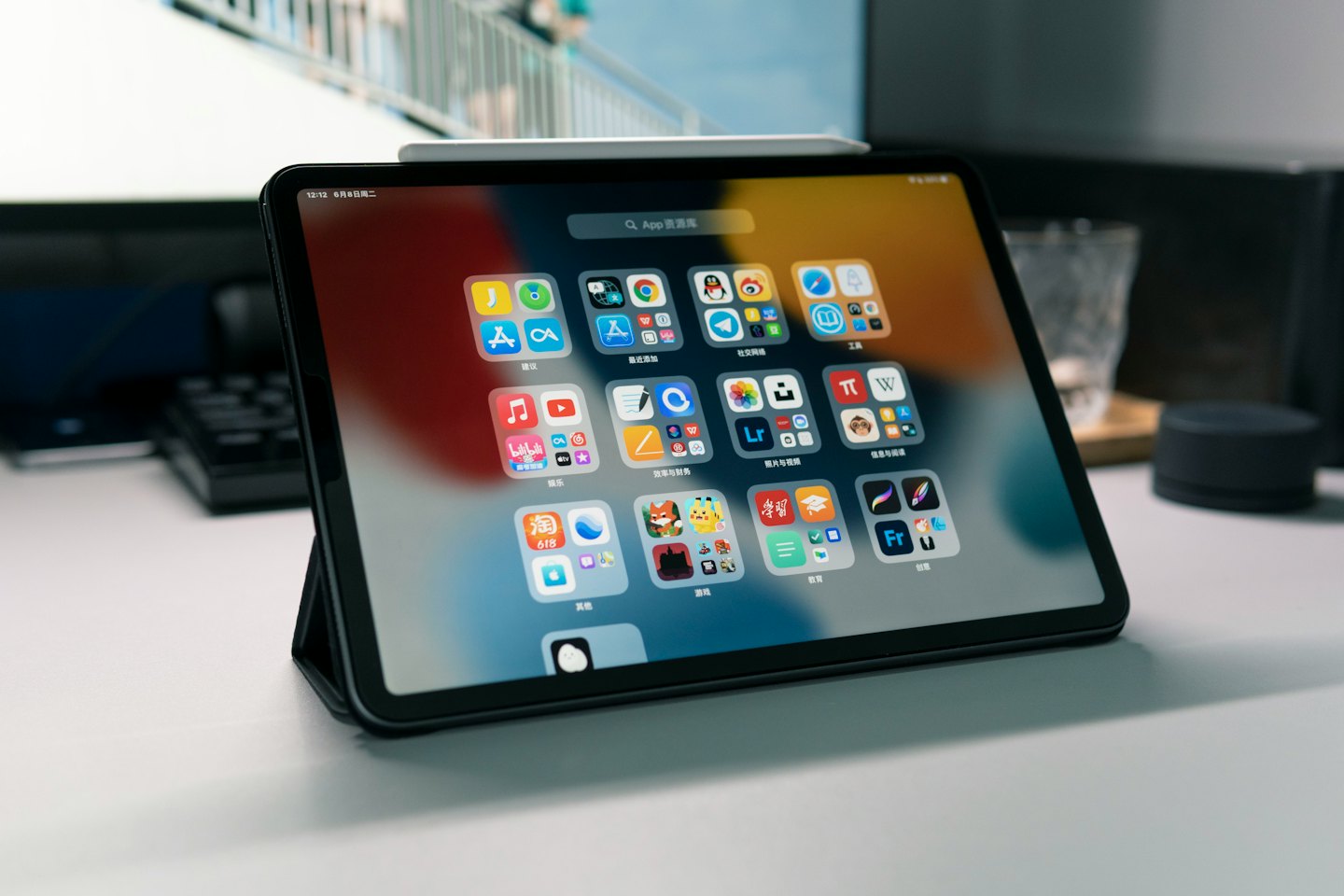 Tablet z kolorowymi ikonami aplikacji leży na białym biurku.